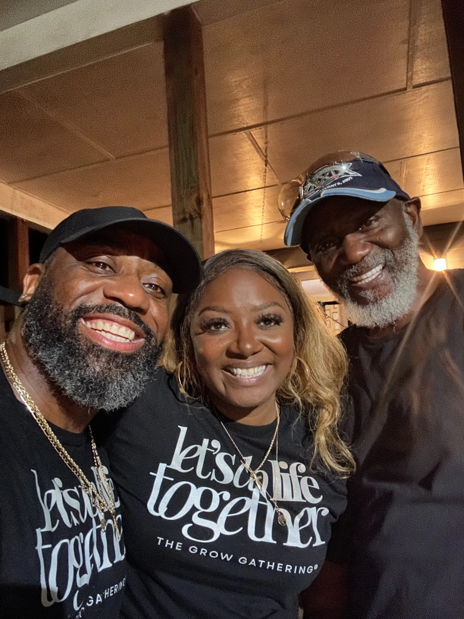 Three people at an evening gathering featuring Let's Do Life Together Grow Gathering shirts