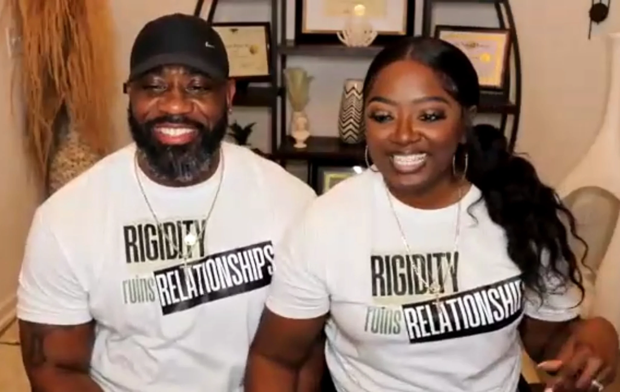 Two people wearing matching white Rigidity Ruins Relationships shirts