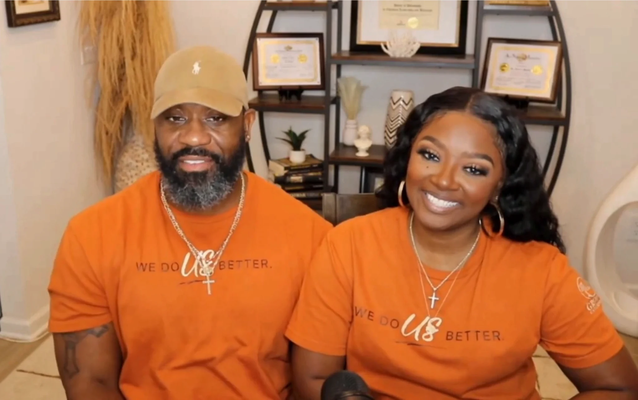 Two people wearing matching orange We Do Us Better shirts
